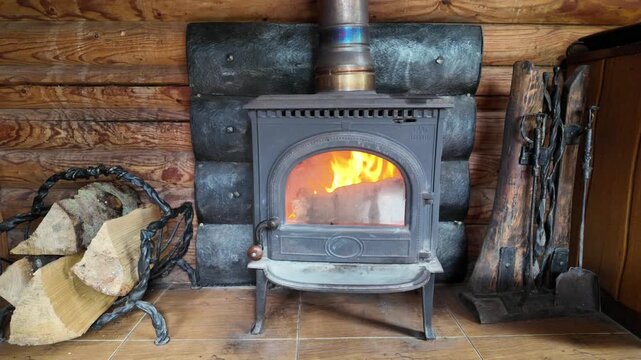 Burning Wood Stove Fireplace in Rustic Wooden Log Cabin Interior