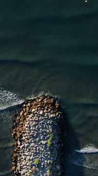 Top Down Aerial View of Waves Crashing on Rock Breakwater