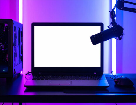 Modern gaming setup with a blank white laptop screen, microphone, and neon purple lighting in a dark room. This nobody, no people tech scene evokes creativity for streaming and digital content.