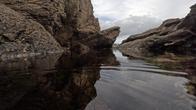 Plunge into rock pool and  underwater tracking shot along algae  bubbling with oxygen produced by photosynthesis. At the base of the cliffs near Fowey, Cornwall, UK