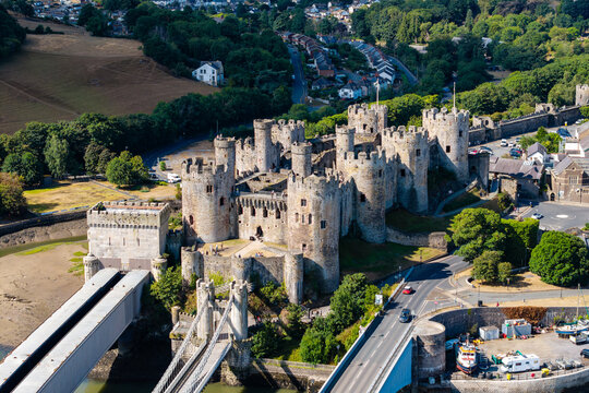 Conwy Castle with stone towers and suspension bridge in Wales, historic medieval fortress rising above river estuary on sunny day