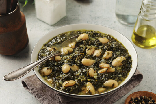A bowl with traditional Tuscan kale salad and white beans soup Cavolo nero e fagioli