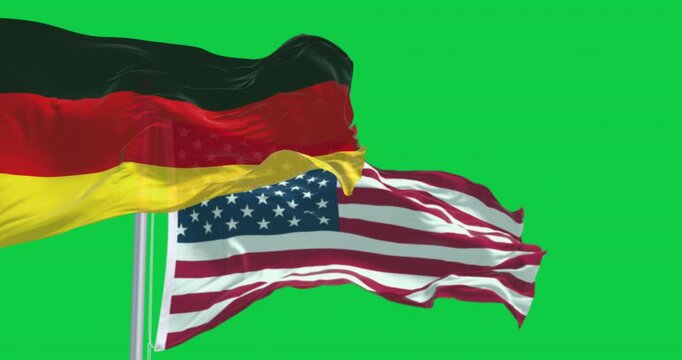 Flags of Germany and the USA waving in the wind isolated on green background
