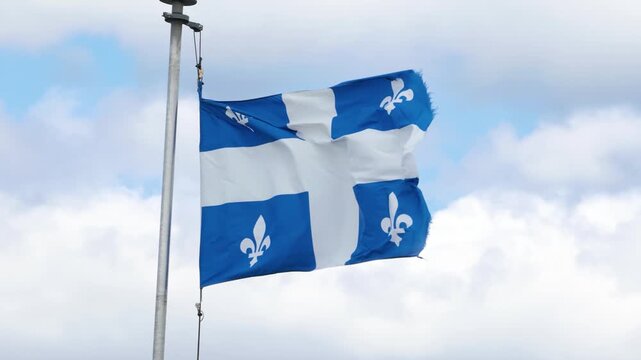 Tattered Quebec Flag Fluttering in Strong Wind Against Sky