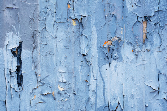 Weathered blue paint peeling and cracking on wooden wall surface, full frame texture