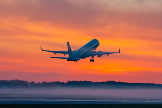 Take off of passenger aircraft at picturesque dawn with a fog