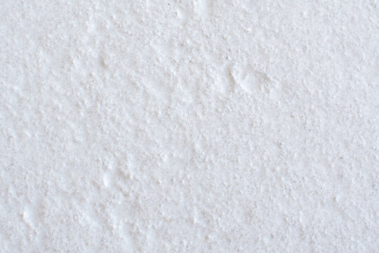 A white, textured porcelain tile surface that creates a subtle abstract background texture