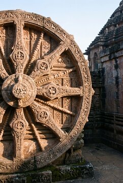 Konark Sun Temple stone chariot wheel with intricate carvings in golden sunlight, Odisha, India