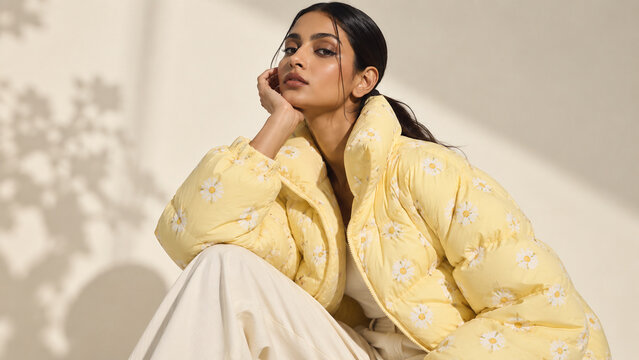High-fashion portrait of a woman in a cream puffer jacket with delicate yellow floral pattern, ideal for winter fashion, beauty, editorial and advertising campaigns.