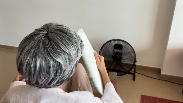 Mujer con sofocos de menopausia vista desde atr&aacute;s en sill&oacute;n