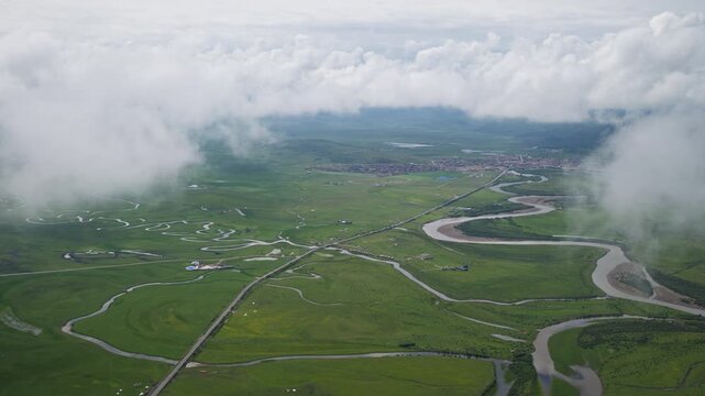 High-Angle Aerial Panoramic View of Meandering Baihe River and Waqie Town in Hongyuan, Aba, Sichuan: Winding Water System, Sea of Clouds, Green Grassland and Horizon Background