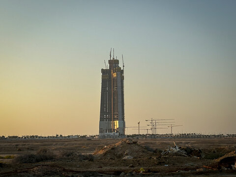 Construction cranes crown the unfinished Kingdom Tower against a clear blue sky, Makkah, Jeddah, Saudi Arabia
