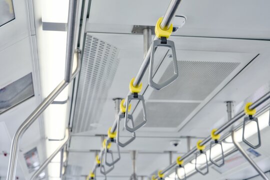 Row of yellow handles and handrails hanging inside public transport train