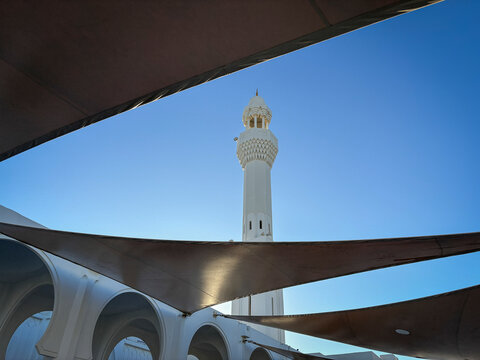 A triangular shade sail slices across the sky beside the minaret of the Al-Rahmah Mosque, Makkah, Jeddah, Saudi Arabia