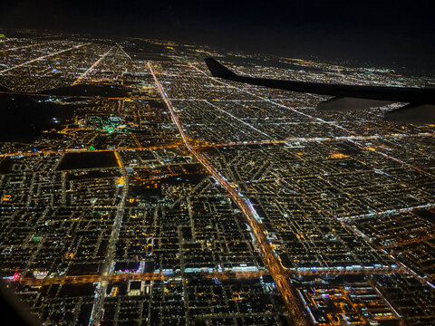 An aircraft wing frames the illuminated street grid of the city at night, Riyadh, Riyadh, Saudi Arabia