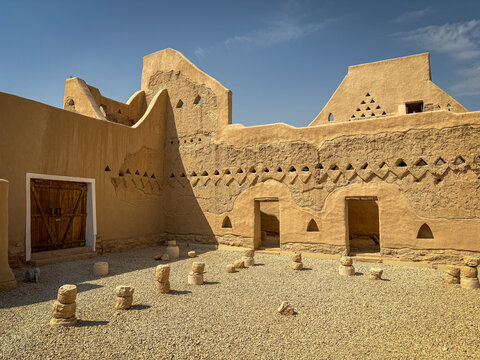 A carved wooden door sits within the mud brick walls of a restored courtyard, Riyadh, Riyadh, Saudi Arabia