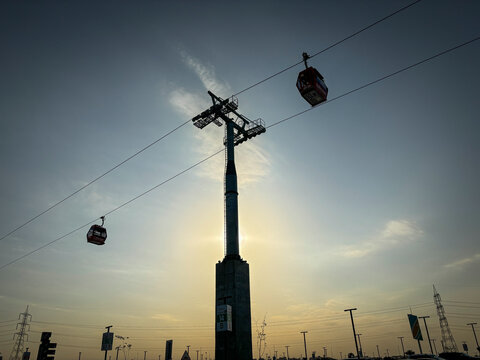 Two cable cars cross a tall pylon silhouetted against the setting sun, Riyadh, Riyadh, Saudi Arabia