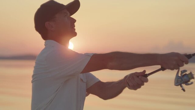 Young man fishing on the river during sunset and casts a lure