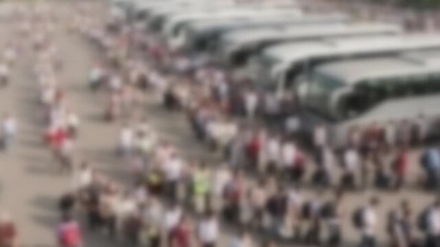 Blurred queues of passengers boarding coaches at a busy bus terminal