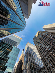 American flag flying high among New York City skyscrapers. Upward shot of an American flag blowing...