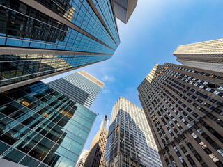 Wide angle low perspective of Manhattan business skyscrapers. Looking up at tall modern office...