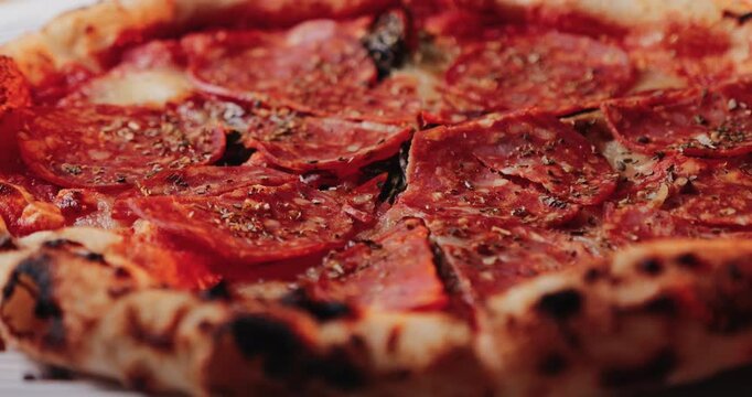 Close up shot of spicy salami pizza with melted cheese and herbs.