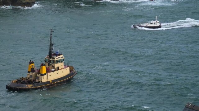 Pilot boat and tug waiting for a china clay ship to enter fowl harbor, Cornwall, uk