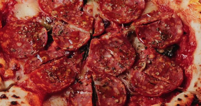 Close up shot of spicy salami pizza with melted cheese and herbs.