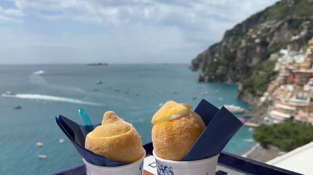 Two lemon sorbets served in lemon shells with the town of Positano in the background, Amalfi Coast, Italy
