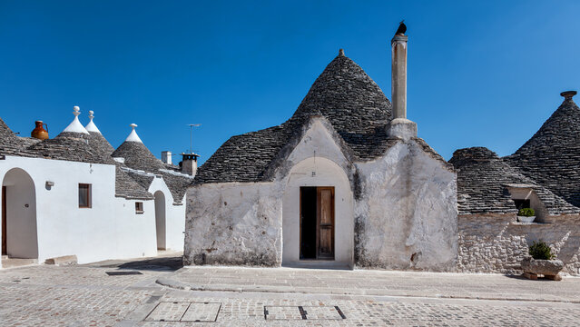 A traditional trullo dwelling with drystone corbelled conical roof, lime-washed walls and stone pinnacolo finial, Alberobello, Puglia, Italy.