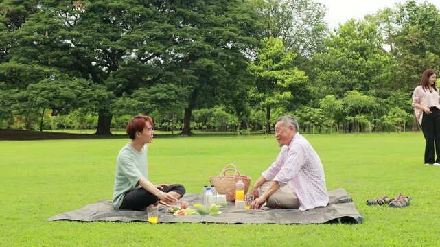 child runs with mother in summer field, small child playing on the lawn. spending time with father in the park. Happy Asian family having fun time on picnic at city nature park, outdoor activitie