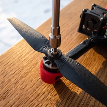 Close-up of tightening a propeller nut on an FPV racing drone brushless motor using a socket wrench on a wooden workbench