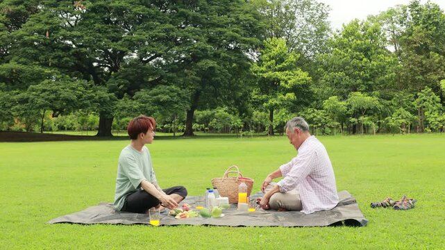child runs with mother in summer field, small child playing on the lawn. spending time with father in the park. Happy Asian family having fun time on picnic at city nature park, outdoor activitie