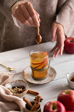 Pouring honey into apple cider, autumn drink lifestyle close-up