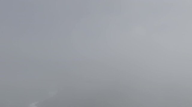 Raw untrimmed aerial drone to shoreline from mist fog.&mdash; take 4