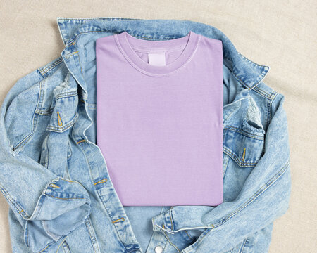 Blank light purple folded shirt mockup over blue denim jacket, crewneck template for print on demand