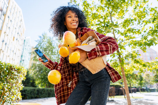 Woman dropping groceries and fruit on city street