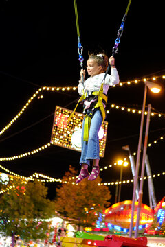 Young girl enjoying bungee trampoline ride at night carnival