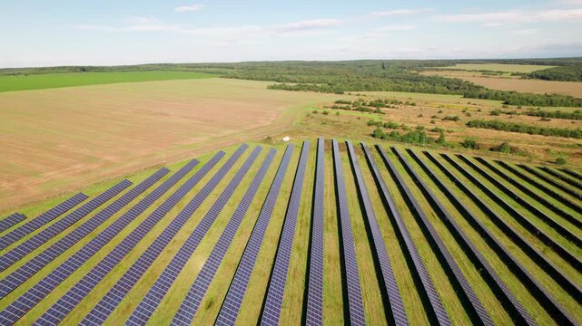 Drone view of photovoltaic installation in open countryside. Parallel module lines create strong visual for clean electricity, engineering, and environmental progress