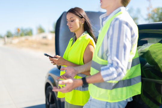 People wearing safety vests dealing with car breakdown