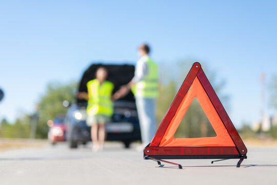 Emergency warning triangle signaling car breakdown on road