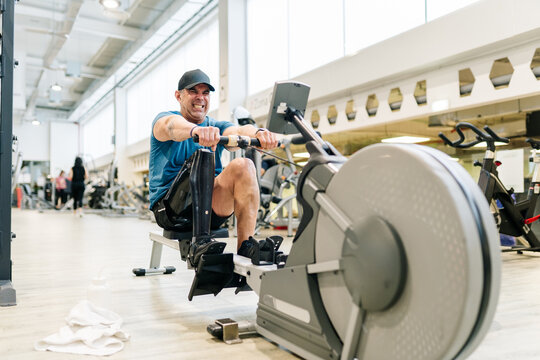Amputee man training hard on a rowing machine