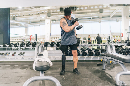Amputee man training bicep with dumbbell in gym
