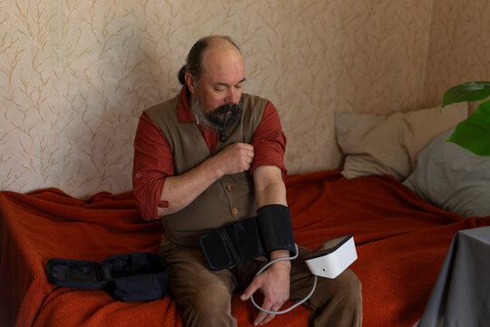 A pensioner is checking his blood pressure.