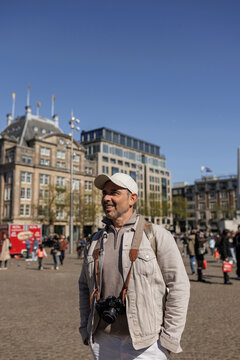 Confident Male Traveler Smiling at Amsterdam Plaza