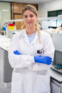 Woman in Lab Coat Stands in Laboratory With Arms Crossed