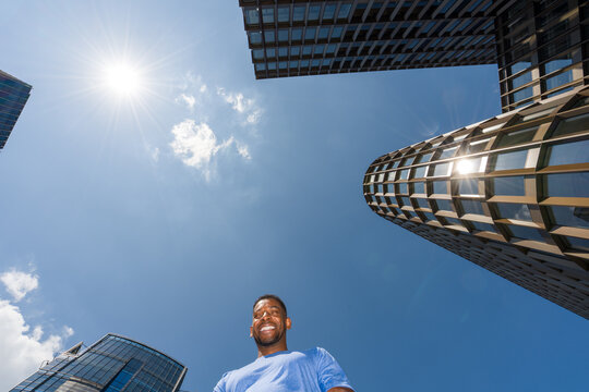 Man Smiling Near Tall Buildings on Sunny Day