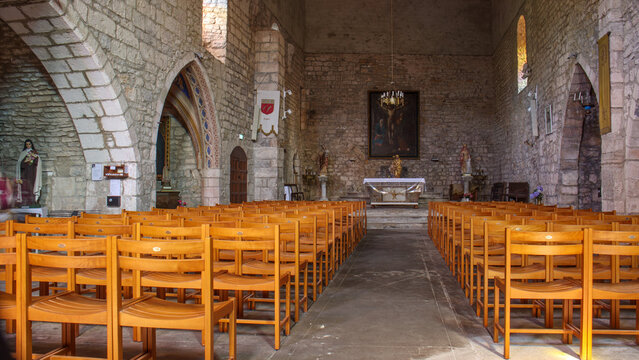 Int&eacute;rieur de l'&eacute;glise de Penne, avec des murs en pierre brute et des arcs gothiques sous un &eacute;clairage tamis&eacute;, &agrave;l'ambiance calme et contemplative.