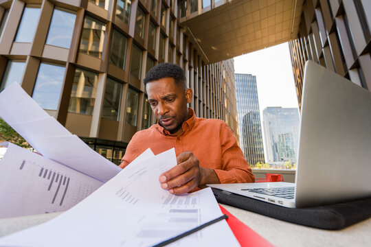 Man Works With Papers and Laptop in Urban Environment