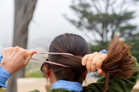 Woman Tying Hair in a Ponytail Outdoors on a Cloudy Day